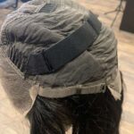 Human hair wig natural very dark brown wavy hair, side view of adjustable strap.